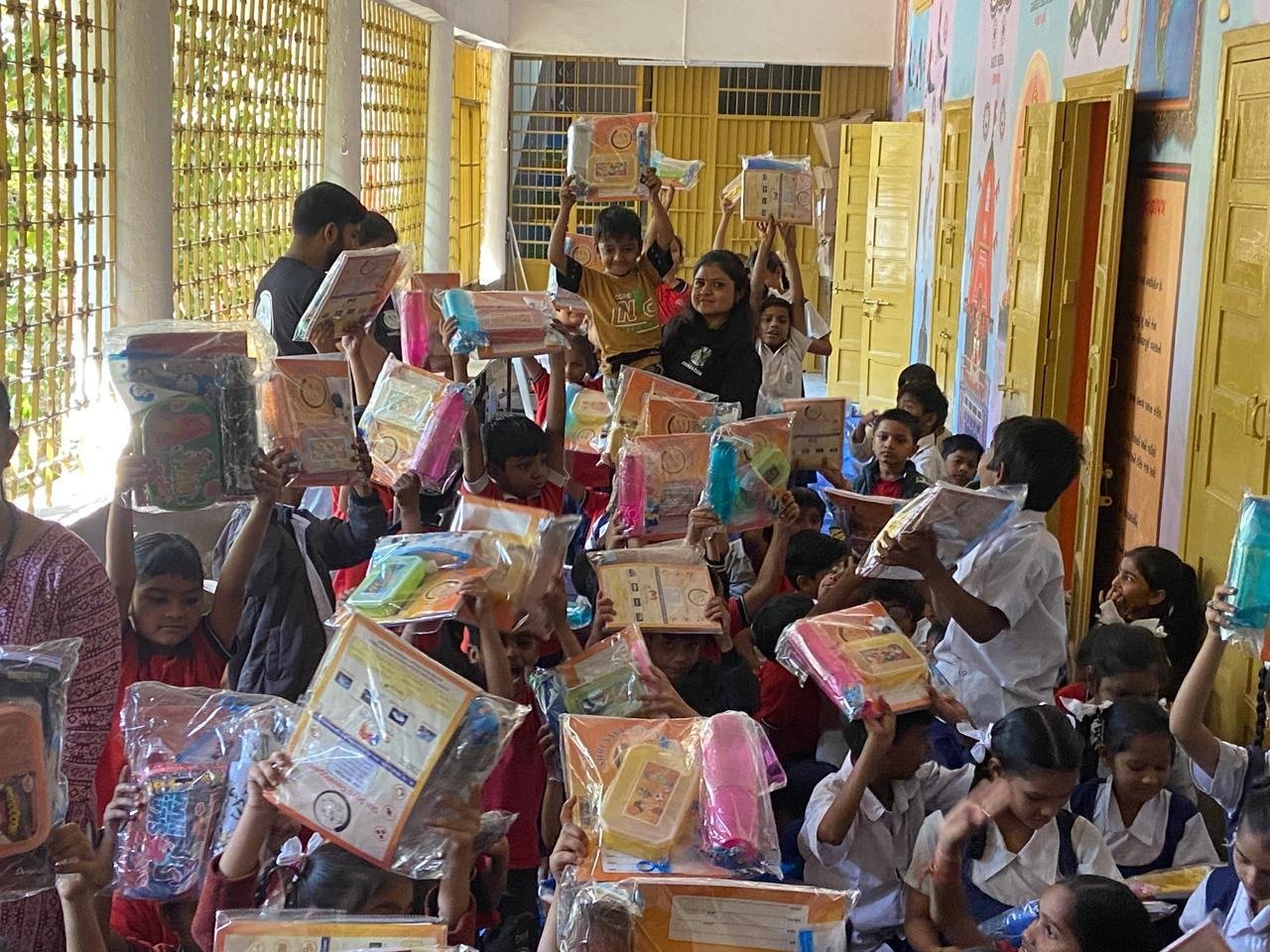 Children raising their hands during a school kit distribution